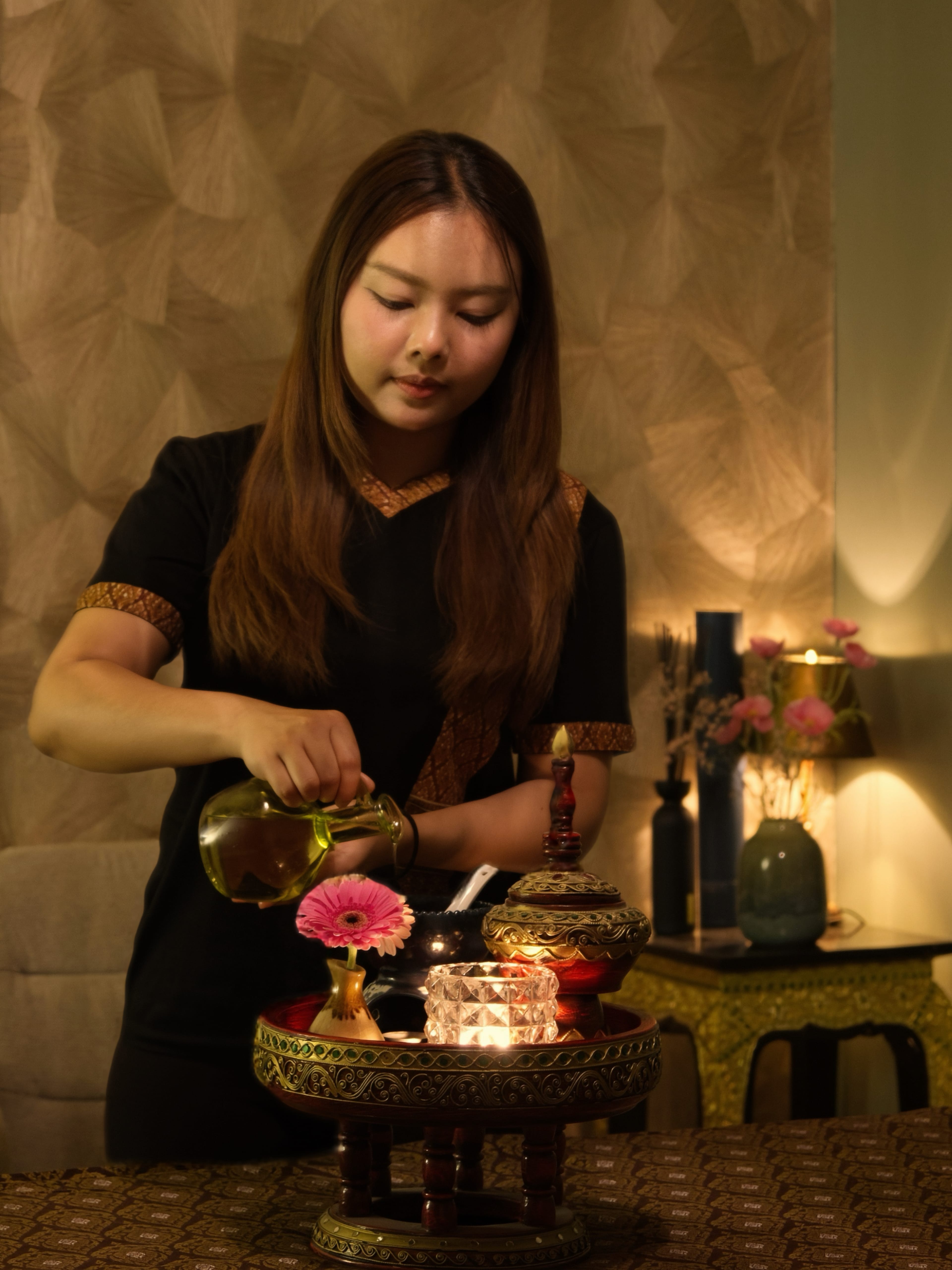 Thaise masseuse van Sukhumvit schenkt warme massageolie in tijdens de voorbereiding in Naarden