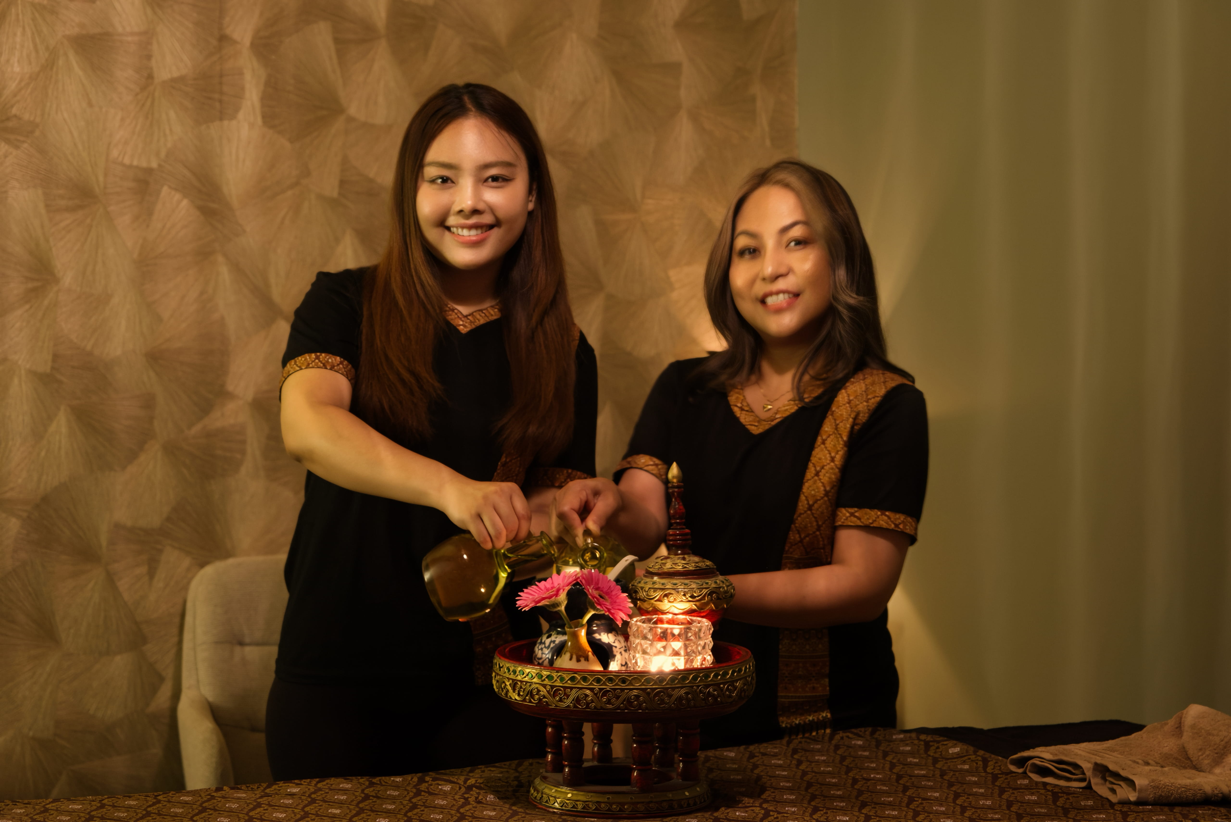 Twee Thaise masseuses van Sukhumvit bereiden een ontspanningsmassage voor met warme oliën in Naarden